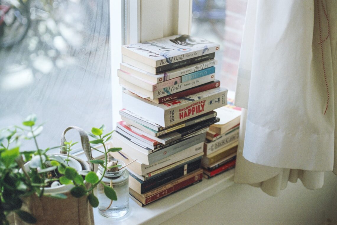 una pila di libri accanto alla finestra