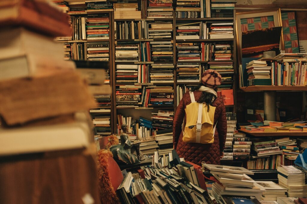 una ragazza con uno zaino davanti a uno scaffale pieno di libri