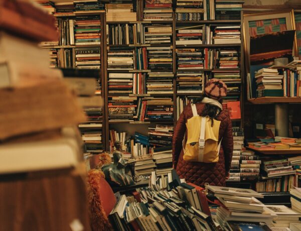una ragazza con uno zaino davanti a uno scaffale pieno di libri