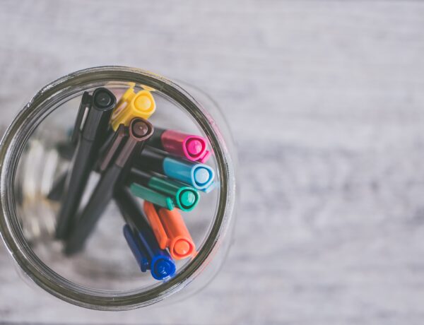 un gruppo di penne colorate in un barattolo di vetro, inquadrate dall'alto